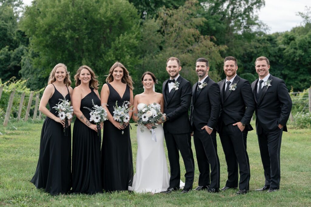 Tabor hill weddings bride and groom with wedding party in vineyard wearing black and white