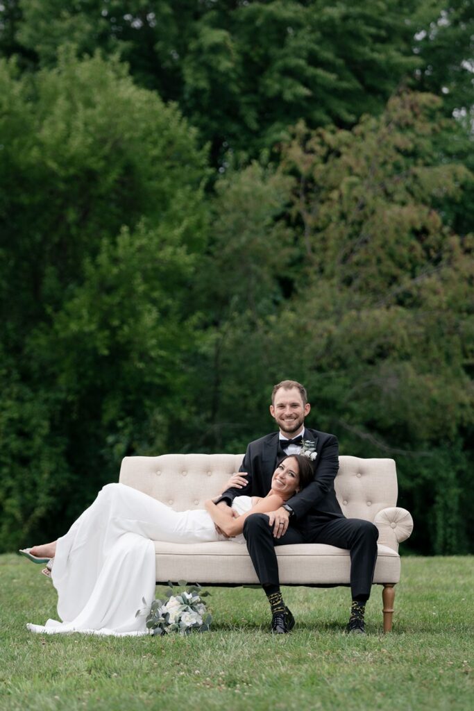 beautiful bride and groom sit lovingly on White Dahlia events Joanie Love Seat in Tabor Hill Weddings Vineyard