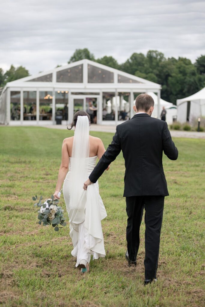 bride and groom walking toward tabor hill weddings reception tent